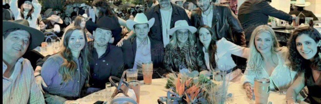 Group of Friends Posing Around a Banquet Table at a Crowded Event, Wearing Hats and Smiling at the Camera. - Tu Vecino Informa