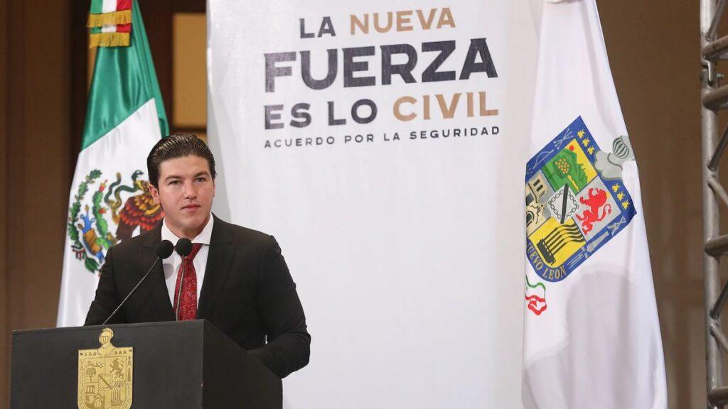Man in a Dark Suit and Red Tie Giving a Speech at a Podium, with Mexican Flag and a White Banner Behind That Reads 'la Nueva Fuerza Es Lo Civil'. - Tu Vecino Informa