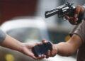 a Street Robbery Scene with a Person Handing over a Smartphone While Another Person Points a Revolver at Them. - Tu Vecino Informa