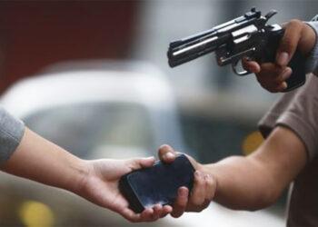 a Street Robbery Scene with a Person Handing over a Smartphone While Another Person Points a Revolver at Them. - Tu Vecino Informa