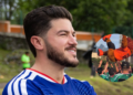 Man with Beard in a Blue Jersey Outdoors; Circular Inset Shows a Crowd Lifting an Orange-clad Teammate in Celebration. - Tu Vecino Informa