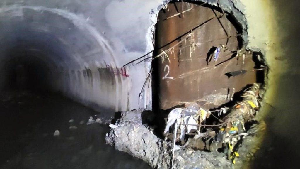 Underground Tunnel with a Shattered Wall Section, Exposed Reinforcement Bars, and Piles of Rubble on the Floor to the Right. - Tu Vecino Informa